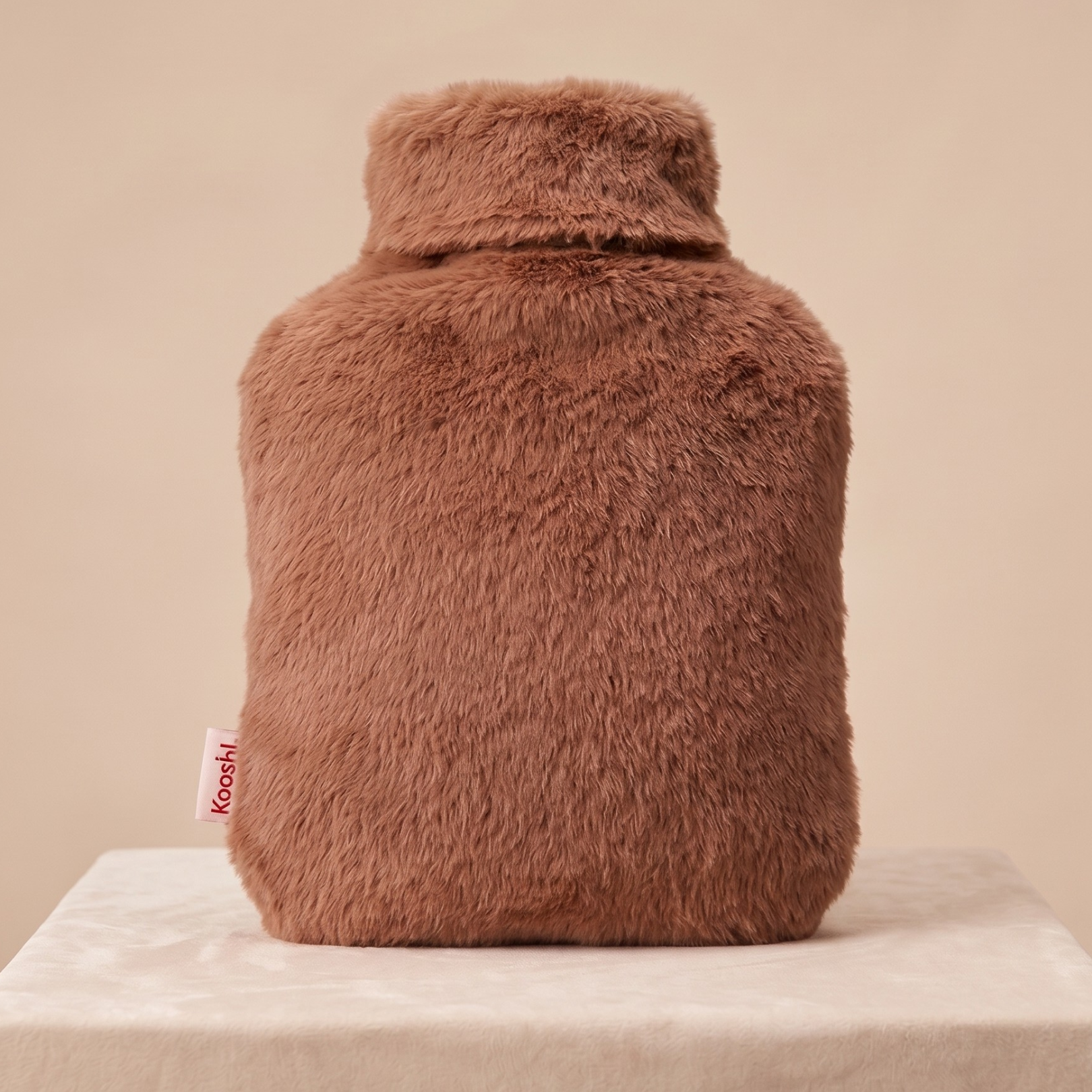 Brown fluffy hot water bottle on a beige background